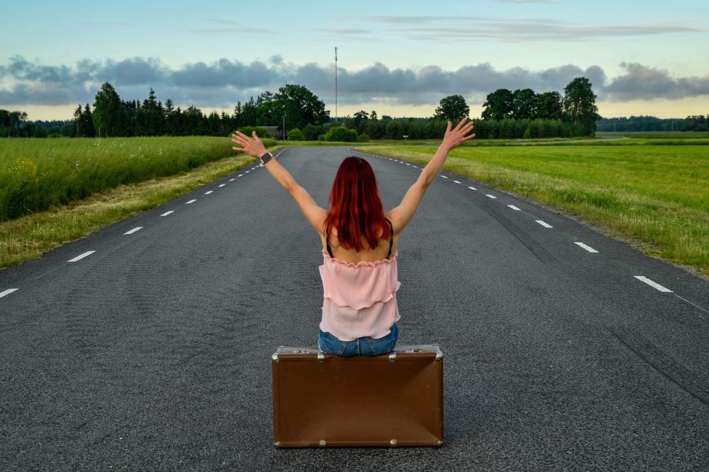 woman with suitcase on countryside road